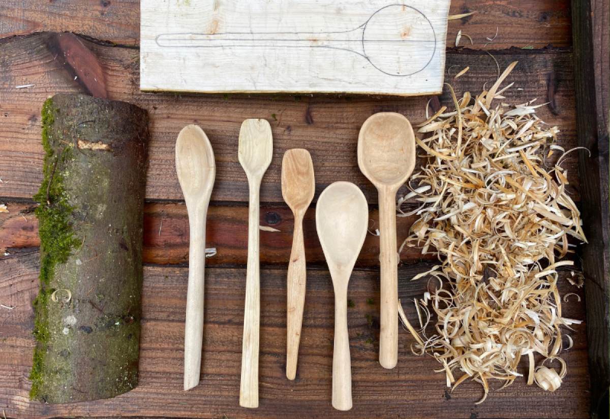 An image showing the various stages of carving a spoon, including the finished spoons in the middle